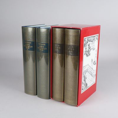 three books are sitting in a red box on a white surface