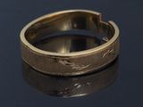 a close up of a gold wedding ring on a black surface