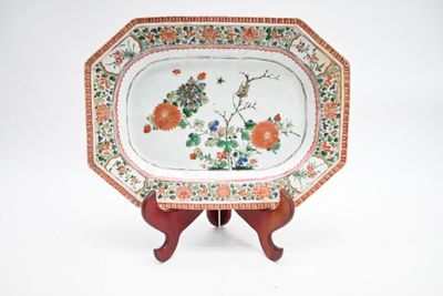 une assiette décorée de fleurs et d'oiseaux, posée sur un socle