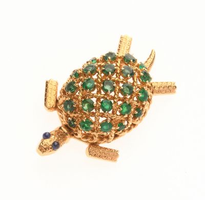 une photo d'une broche en forme de tortue en or, ornée de pierres vertes et bleues