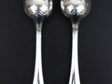 two silver spoons on a black surface with a black background