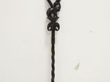 an old iron key is hanging on a wall near a white wall