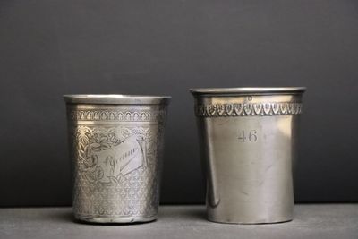 deux tasses en argent posées l'une à côté de l'autre sur une table