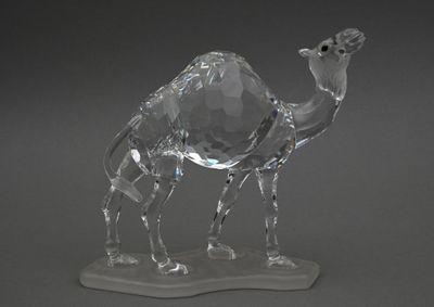 une figurine en cristal représentant un chameau, posée sur un socle
