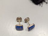 pair of lapis and silver cufflinks on a white surface