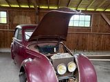 une vieille voiture, le capot ouvert, dans un garage