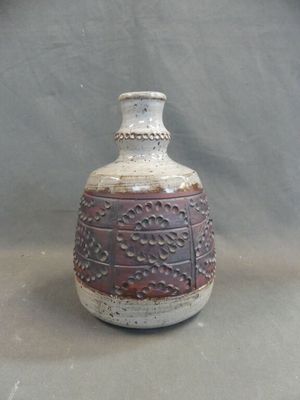 a brown and white vase sitting on a gray surface