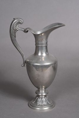 a silver pitcher with a handle on a table