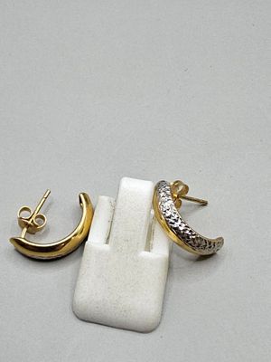 two pairs of gold and silver earrings on a white surface