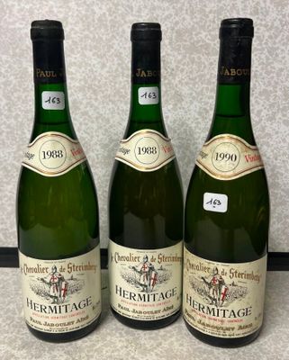 trois bouteilles de vin sont alignées sur un plan de travail