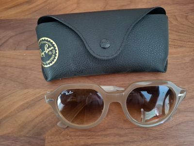Des lunettes de soleil Ray-Ban et leur étui posés sur une table en bois
