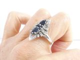 a woman ' s hand holding a diamond and sapphire ring
