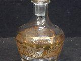 a clear glass bottle with a gold design on it
