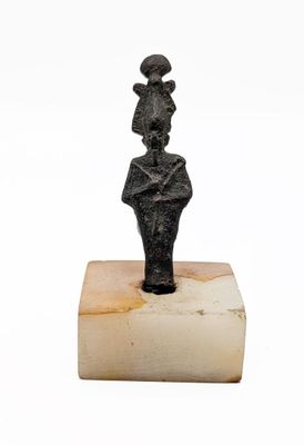 une image représentant une statue de femme coiffée d'un chapeau, posée sur un bloc de marbre