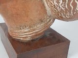 a brown vase on a wooden stand with a white background