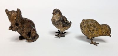three small figurines of animals on a white surface