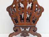 carvings on the back of a wooden chair with wheels on a white surface