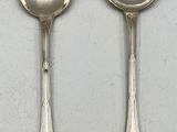 two silver spoons and a spoon on a white surface