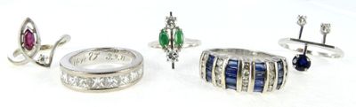 three rings and a ring with different colored stones on a white surface