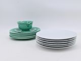 des assiettes et des bols verts et blancs posés sur un plan de travail blanc
