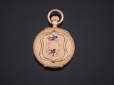 a close up of a gold pocket watch with a blue bird on it
