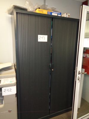 une grande porte métallique sur laquelle est accrochée une pancarte, dans une pièce