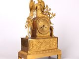 a gold clock with an angel on top of it