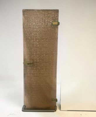 un grand vase en verre avec un socle en métal posé sur une surface blanche