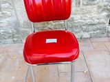 a red chair that is sitting in front of a stone wall