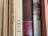 several old books are stacked on a shelf in a box