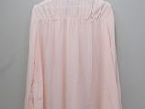 a pink blouse hanging on a hanger against a wall