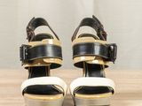 black and white high heeled sandals with buckles on a wooden surface