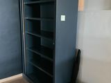 a black bookcase and a suitcase in the corner of a room