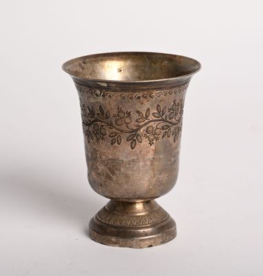 un vase en argent posé sur une surface blanche