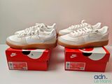 une paire de baskets Nike blanches posées sur une boîte rouge