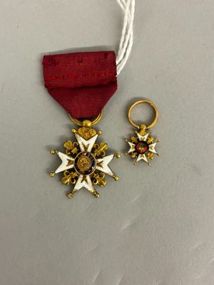 deux médailles d'or et un ruban rouge sur un fond blanc