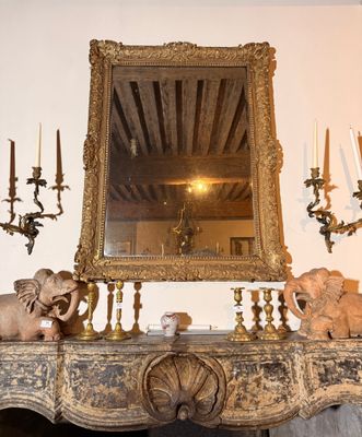 une cheminée sur laquelle sont posés un miroir, des bougies et des statues