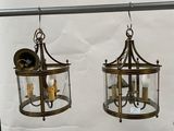 two lanterns hanging from a metal pole on a white wall