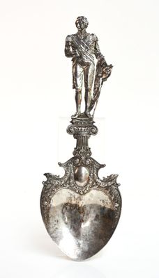 une figurine en argent représentant un homme posé sur un cœur