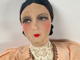 a doll that is wearing a pink dress and a necklace
