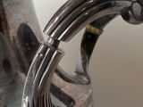 a silver vase that has a handle on it