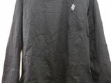 a black long sleeved shirt hanging on a hanger on a wall