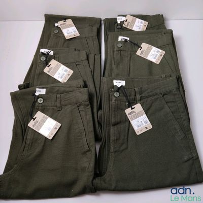 cinq paires de pantalons, encore étiquetées, posées sur une table