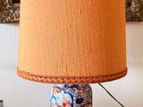une lampe posée sur une table, avec un tableau accroché au mur en arrière-plan