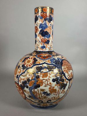 an orange and blue vase sitting on top of a white table
