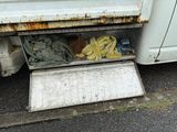 a dirty white truck with a bunch of dirty clothes in it