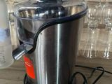 a silver juicer sitting on a table next to a bottle of vodka