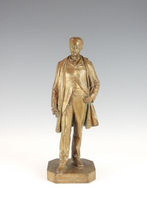 bronze statue of a man in a suit and tie standing on a pedestal
