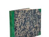 an old book with a green cover sitting on top of a white surface