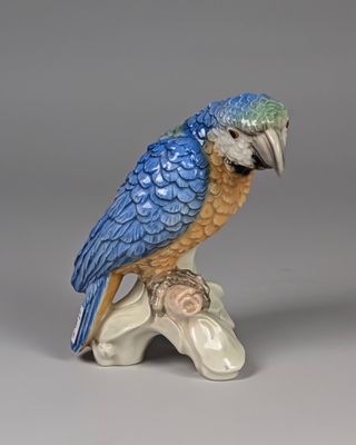 une figurine représentant un oiseau bleu et jaune perché sur une branche
